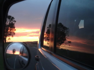 Passenger side mirror view of the sunset along the Great Ocean Road