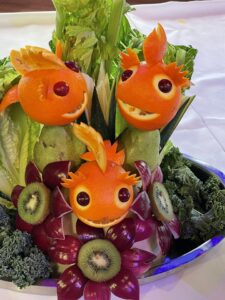 Fruit and Vegetable carvings on cruise ship three orange fishes in a sea of kiwi, purple and green vegetables