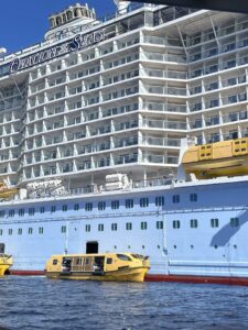 View of Ovation of the Seas mid ship with eighteen decks and yellow lifeboats used for tendering 
