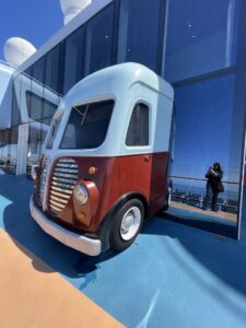 Artwork breaking through the wall of the top deck its the front of a bus with white top and red bottom