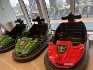 Three bumper cars in green and red with royal caribbean anchor logo on cruise ship