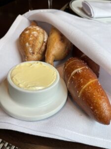 Bread basket with sourdough, pretzel and multigrain rolls and butter container