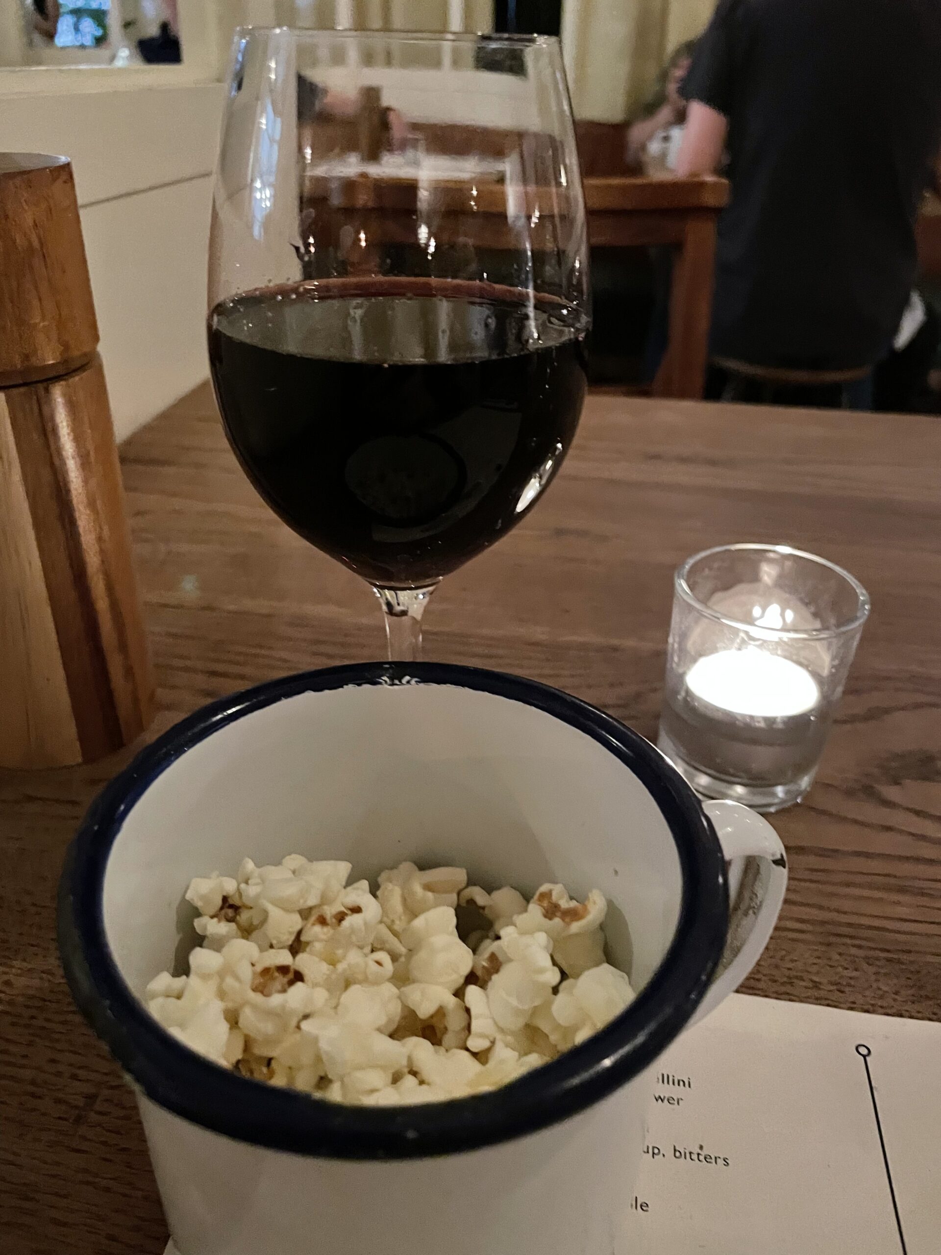 Glass of red wine and mug of popcorn at Flat Iron Steak London
