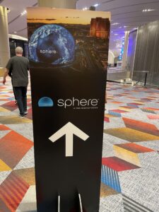 Sign with arrow pointing direction to the Sphere with a man on the left side