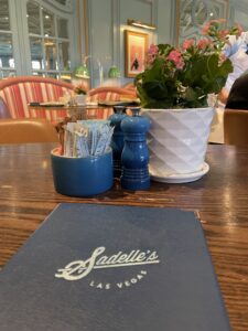 Breakfast menu on table with sugar, table plant and view of tables in background