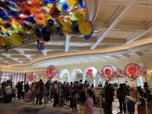 Long line of people waiting in line to check in at Bellagio with colorful glass ceiling artwork by Chihuly