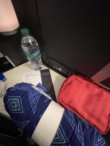 United Polaris at seat included red toiletry bag, blue comforter, bottle of water